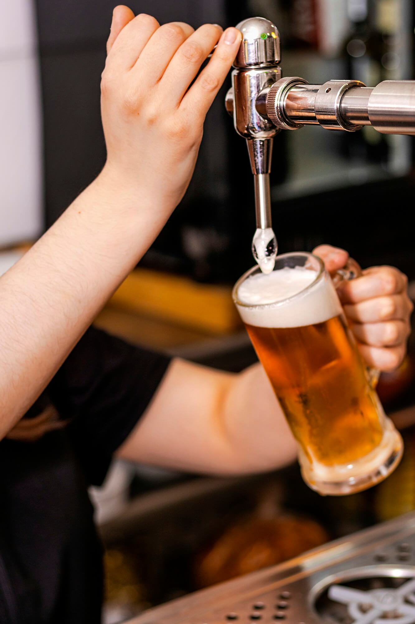 close-up of barman hand at beer tap pouring a draught lager beer