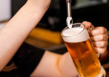 close-up of barman hand at beer tap pouring a draught lager beer